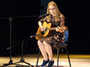na scenie dziewczyna gra na gitarze i śpiewa