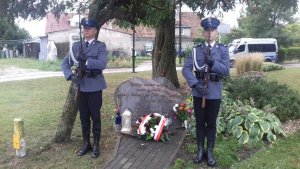 Policjanci stoją przy pomniku ku pamięci poległego Marka Cekały