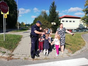 policjant z dziećmi przed przejściem dla pieszych