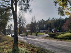 Pierwszy parking przy cmentarzu na Polskiej Wsi i ulica. W tle  policjanci w kamizelkach odblaskowych.
