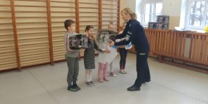w szkole policjantka przekazuje  nagrody-kaski dzieciom