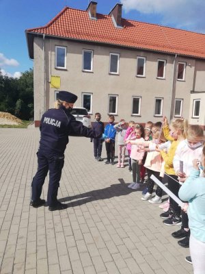 przed szkoła policjantka rozdaje dzieciom opaski odblaskowe