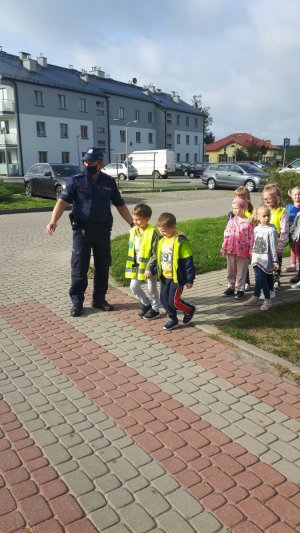 policjant wraz z dziećmi przy przejściu dla pieszych
