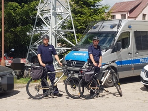 dwóch policjantów stojących przy rowerach stojący na tle radiowozu