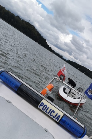 sygnały policyjne z napisem policja, w tle holowana łódź