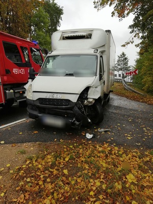 z lewej strony na drodze stoi wóz strażacki z prawej strony stoi samochód iveco koloru białego z uszkodzonym zderzakiem i przednią lampą