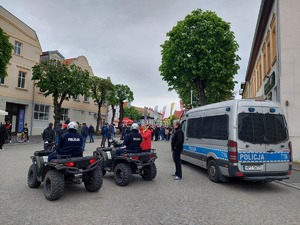 w centrum Mikołajek stoją dwa quady policyjne na nich siedzą policjanci, obok stoi radiowóz policyjny