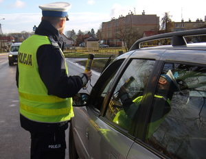 zdjęcie policjanta ruchu drogowego stojącego przy samochodzie z alkomatem