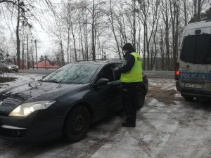 policjant wręcza odblask kierowcy stojącego auta