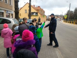policjant z dziećmi na chodniku przy ulicy