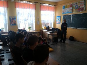 policjantka prowadzi zajęcia w klasie z tyłu uczniowie