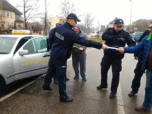 policjanci wręczają odblaski taksówkarzom