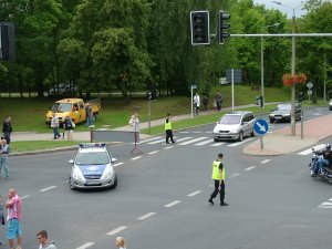 na skrzyżowaniu ulic stoi radiowóz i policjanci kierują ruchem drogowym