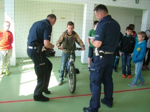 na hali, chłopiec na rowerze obok policjanci