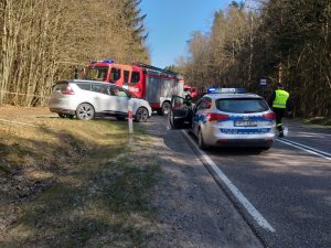 DK58 miejsce wypadku, z lewej strony  w kierunku Nidy stoi radiowóz, z lewej strony na poboczu stoi białe auto osobowe, a za nim czerwony wóz strażacki, obok radiowozu idzie strażak