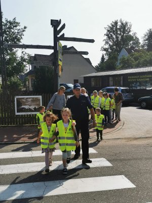 dzieci wraz z policjantami przechodzą przez przejście dla pieszych