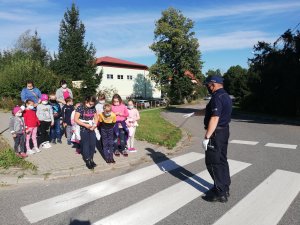 na chodniku przy przejściu dla pieszych policjant i dzieci