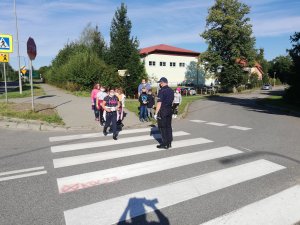 na chodniku przy przejściu dla pieszych policjant i dzieci