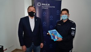 wspólne zdjęcie z lewej burmistrz mrągowa, z prawej komendant powiatowy policji w Mrągowie trzyma ksiązeczkę
