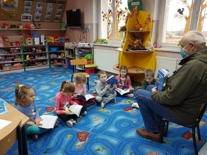 Ryszard Pukas czyta dzieciom książeczkę