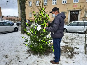 mężczyzna zdejmuje z choinki odblask