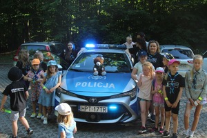 dzieci stojące przy radiowozie policyjnym