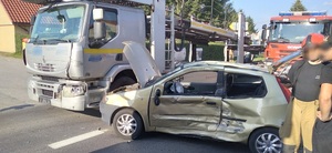 z lewej strony stoi samochód ciężarowy, z przodu samochód fiat z uszkodzonym bokiem