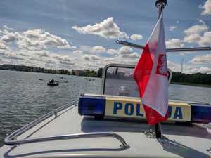 łódź policyjna w tle inne łódki i osoby płynące w jeziorze