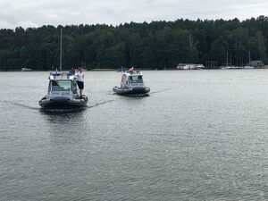 dwie łodzie policyjne na jeziorze i policjant na łodzi policyjnej