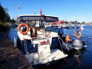 łódź motorowa i stojąca obok łódź policyjna z policjantem