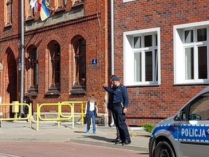 radiowóz policyjny i policjant stojący przed szkołą