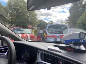 czapka policyjna na kokpicie w samochodzie a w tle kolizja drogowa