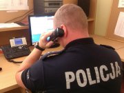 policjant siedzący tyłem na stanowisku dowodzenia ze słuchawką telefonu przy uchu