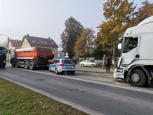 na drodze z lewej strony zdjęcia widać samochód ciężarowy za nim stoi radiowóz a za radiowozem drugi samochód ciężarowy