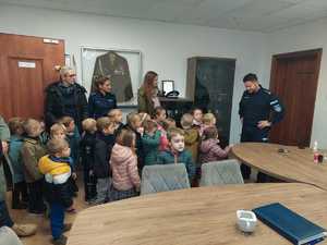 w gabinecie Komendanta Powiatowego Policji w Mrągowie z prawej strony stoi komendant, przed nim stoją dzieci, opiekunki i policjantka