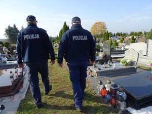 dwóch policjantów idących między grobami