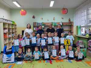 grupa dzieci z dyplomami w rękach, za nimi stoją 2 opiekunki i 2 policjantki