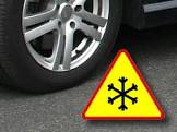 koło samochodu z oponą i znak ostrzegawczy oszronienie jezdni