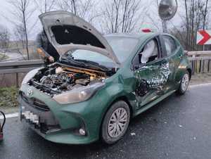 samochód toyota z podniesioną maską i uszkodzonym bokiem od strony kierowcy stojący na drodze