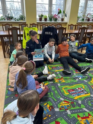 w bibliotece policjantka siedząca obok dzieci na podłodze