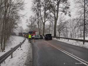 stojące na drodze dwa rozbite samochody osobowe a za nimi stojące wozy strażackie