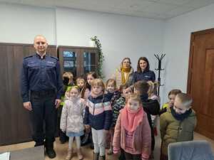 w gabinecie Komendanta, z lewej strony I Zastępca Komendanta Powiatowego Policji z Mrągowie, przy nim stoją dzieci, za dziećmi opiekunka i policjantka