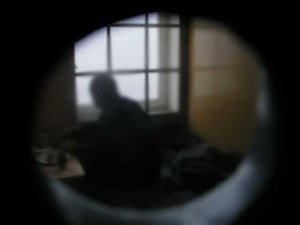 widok przez wizjer do celi w której siedzi mężczyzna