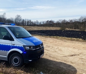 z lewej strony radiowóz policyjny a w tle wypalona trawa
