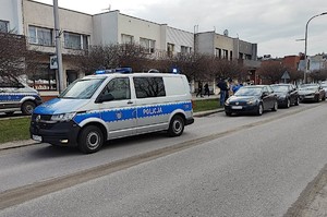 na drodze stojący radiowóz policyjny a za nim zaparkowane samochody osobowe