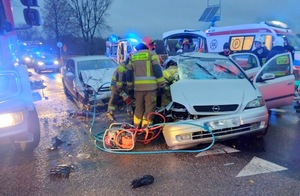 rozbity przód samochodu osobowego i stojący przy nim strażacy