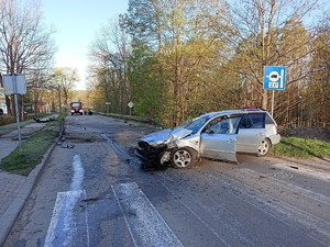 stojący w poprzek drogi przed przejściem dla pieszych rozbity samochód osobowy, w oddali widać wóz strażacki