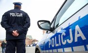 stojący tyłem policjant obok radiowozu