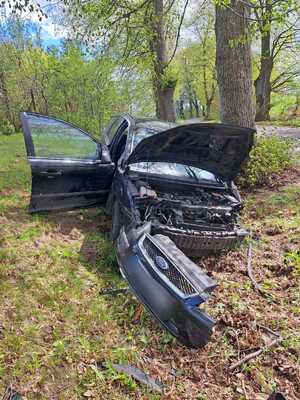 samochód z rozbitym przodem stojący przy drzewie w lesie