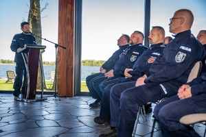 na sali siedzą słuchacze z przodu z lewej strony stoi Komendant Powiatowy Policji w Mrągowie, który przemawia